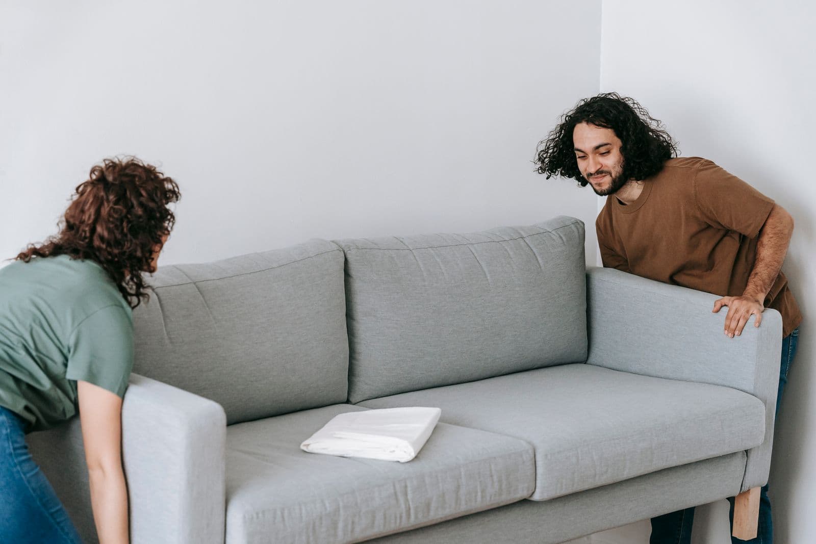 Movers carefully carrying a wrapped sofa